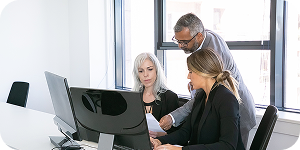 Team collaborating at a desk while customizing a view on their computer.