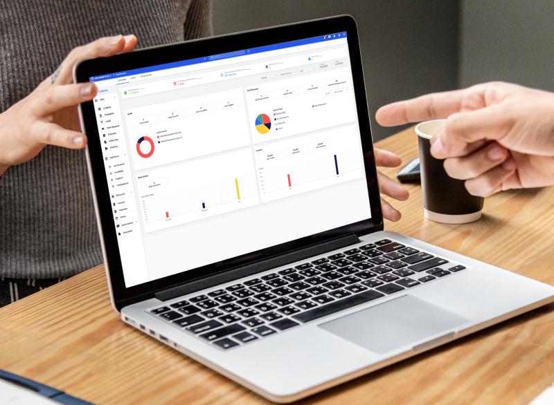 Movegistics CRM dashboard displayed on a laptop with charts and analytics, being reviewed by a team.